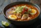Tigela de Asam Laksa com caldo de peixe escuro massa e ervas frescas