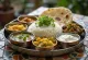 Thali à moda Tamil, servido com pratos indianos variados em tabuleiro de metal: arroz, caris, pães, chutneys