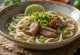Sopa de noodles Phở de carne com caldo quente, servida com ervas frescas e lima