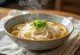 Kake udon servido em tigela, sopa udon básica em caldo dashi, decorada com cebolo fresco e sementes de sésamo