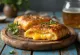Stromboli com queijo fumado servido, com rico queijo fumado por cima, estaladiço por fora e macio por dentro.
