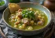Pozole con tomatillo servido com lima, coentros e cebolinho fresco