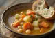 Puchero valenciano servido com legumes de raiz e grão-de-bico com legumes frescos
